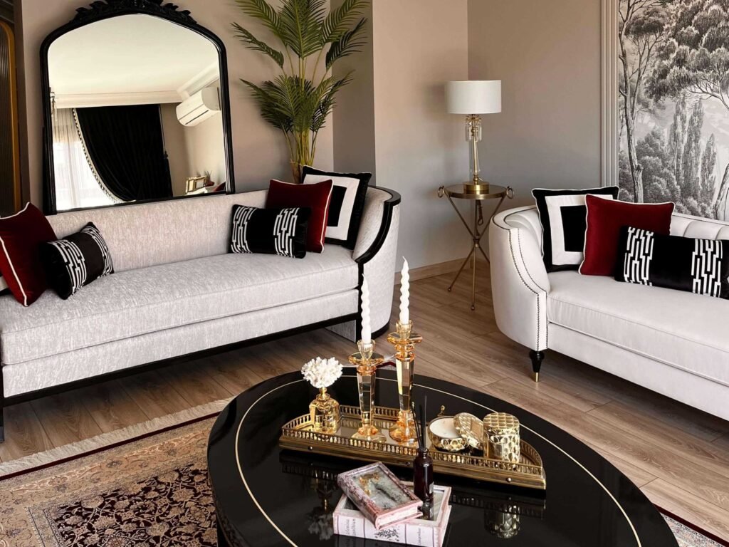 White tufted Chesterfield sofas arranged around a gold-trimmed coffee table.