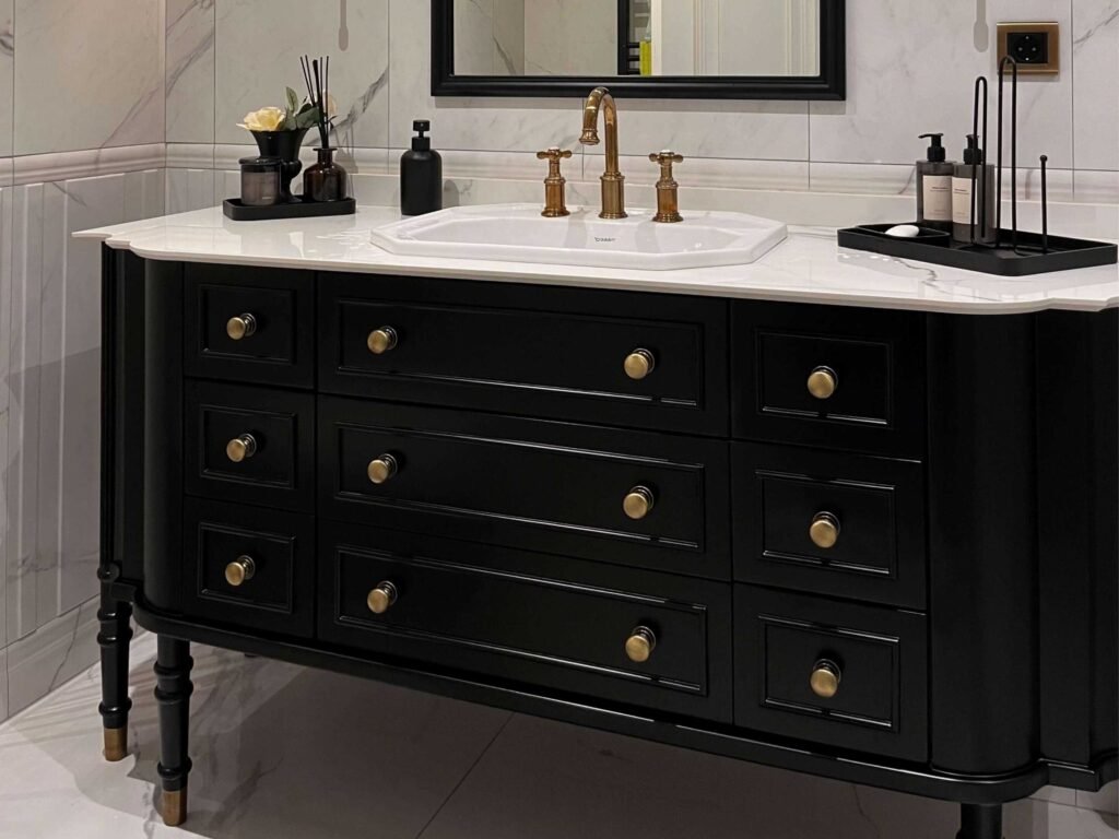 Luxury black bathroom vanity cabinet with brass handles and a white marble countertop.