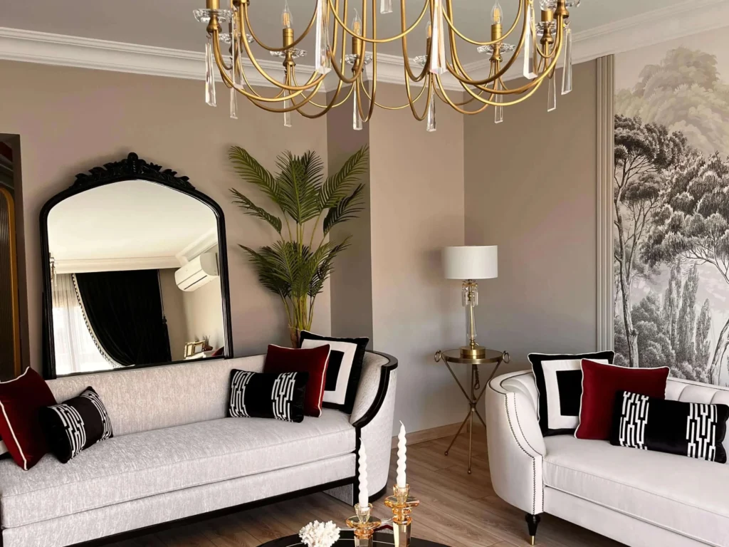 Bright living room featuring a white Chesterfield sofa and large green plants.