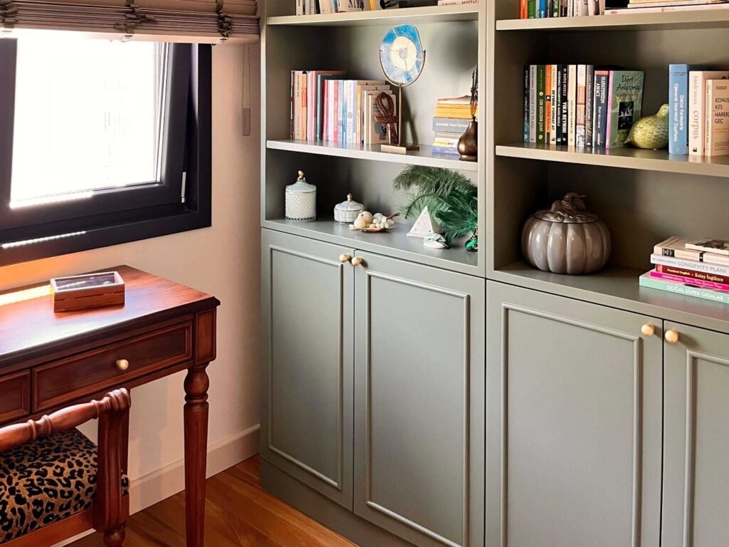 Custom built-in sage green bookcase and classic wooden writing desk design.