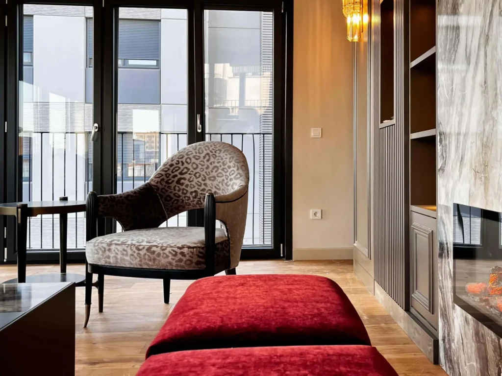 Statement leopard print armchair beside a red tufted velvet pouf.