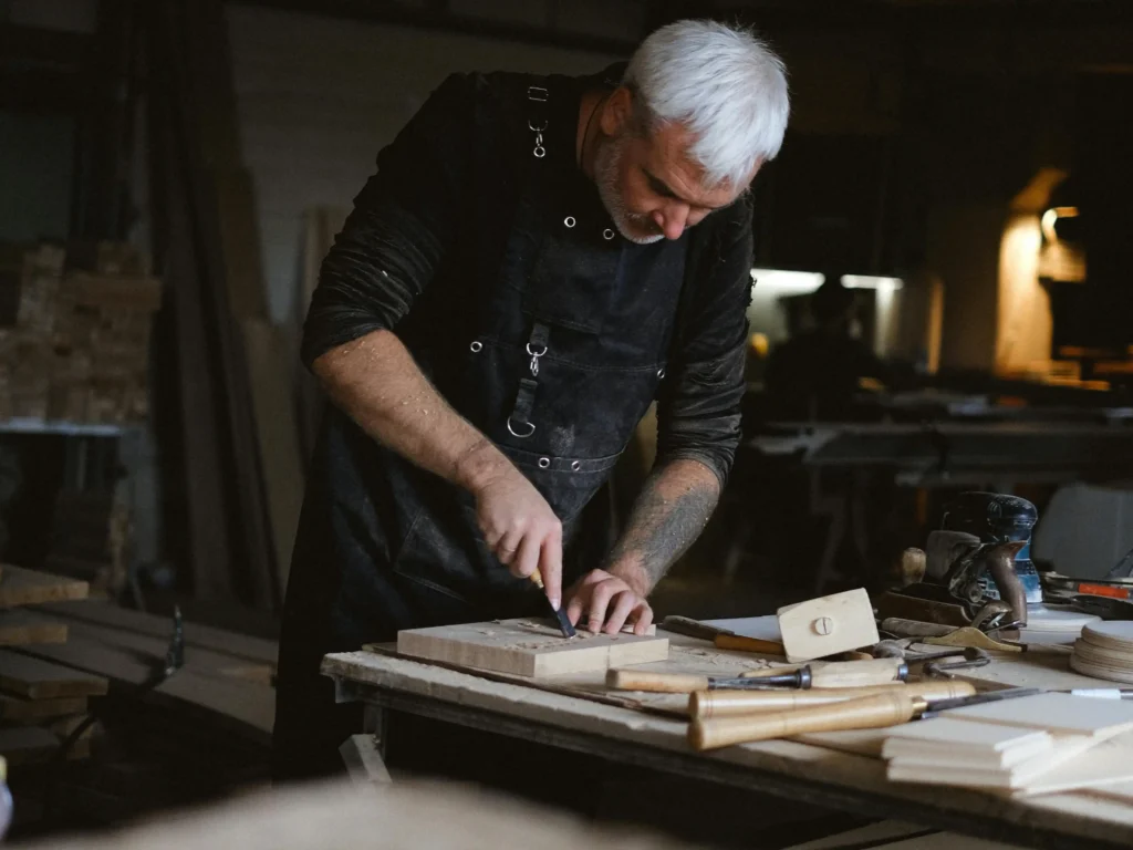 A master craftsman cutting a solid wood block using a circular saw in the traditional furniture workshop